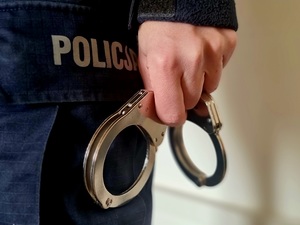 KPP Mielec, kajdanki w ręce na tle spodni policyjnych
