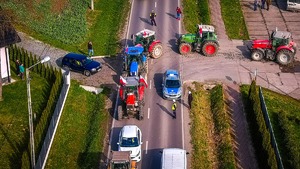 sprzęt rolniczy- ciągniki na drodze, policjanci ruchu drogowego kierujący ruchem drogowym