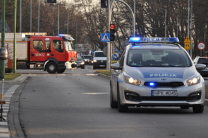 policyjny radiowóz na ulicy w tle radiowóz straży pożarnej i inne samochody osobowe